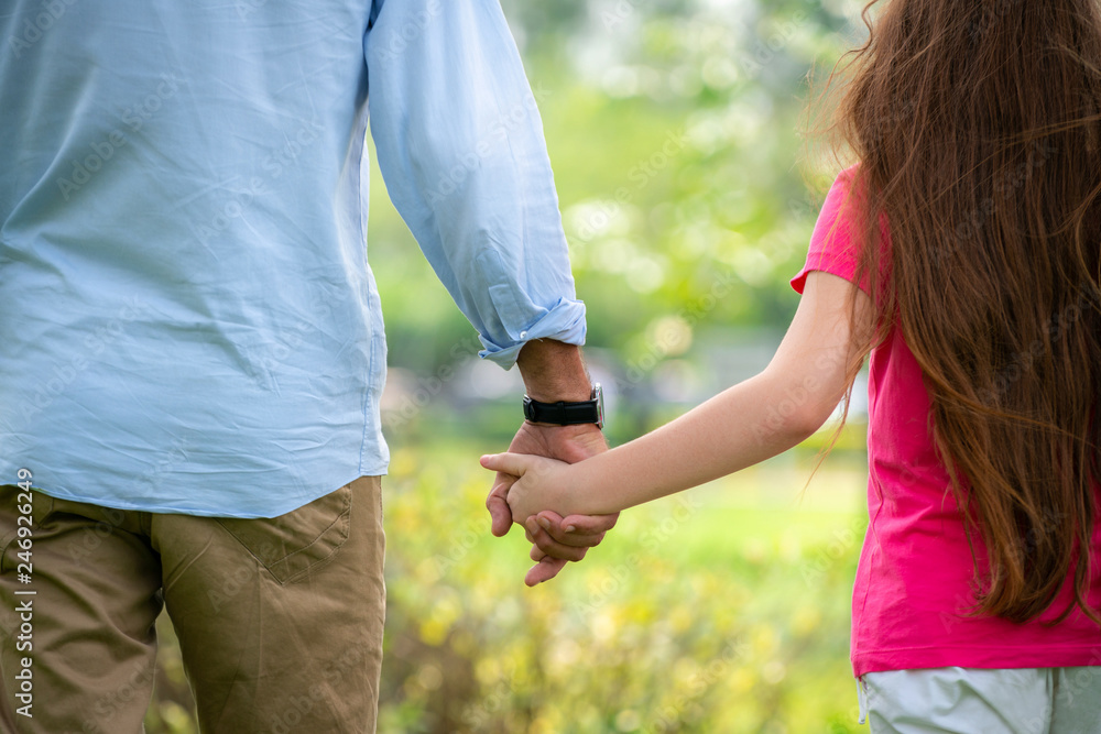 Father and daughter holding hands and walking in the park in summer ...
