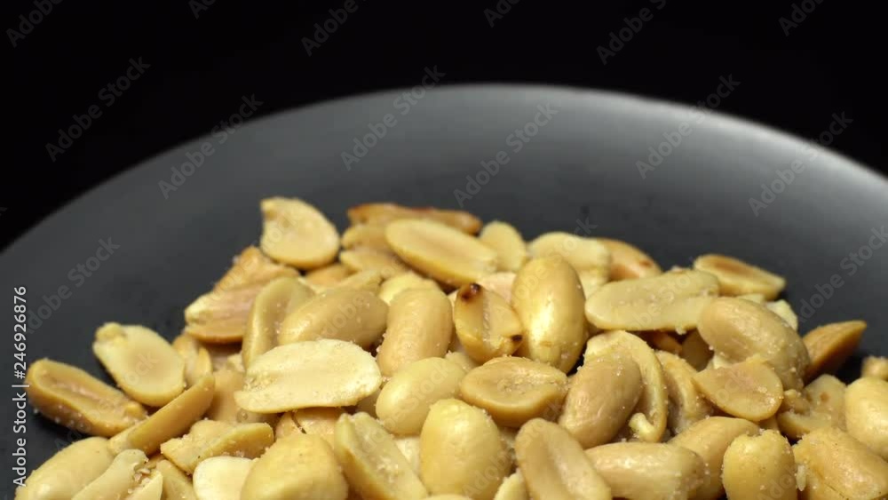 Peanuts. Peeled peanuts fried with salt. Rotation. Snack closeup. Peanuts in a bowl. Selective focus. black background. Studio shot. Peanuts. Peeled peanuts fried with salt. Rotation. Snack closeup. Peanuts in a bowl. Selective focus. black background. Studio shot.