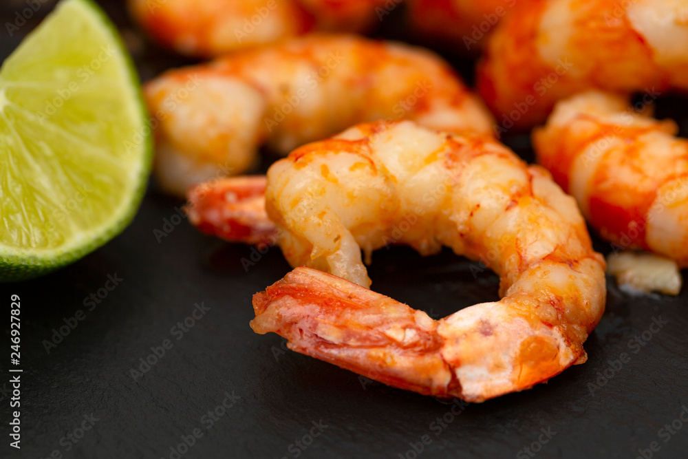 Tasty appetizing roasted shrimps prawns with lime on black background. Tasty appetizing roasted shrimps prawns with lime on black background.
