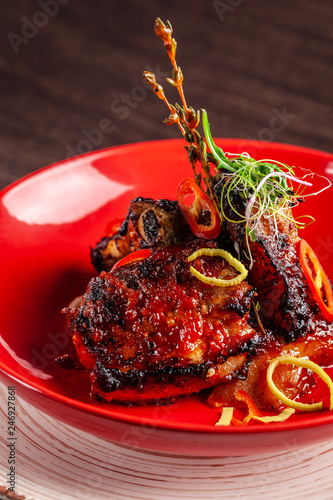 American cuisine concept. BBQ pork ribs baked in honey mustard. Serving dishes in a restaurant in ceramic ware. On the table a glass of red wine. copy space