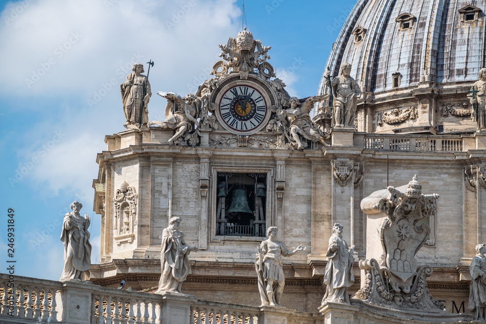 view on Dome of St. Peter's Basilica with statues of apostles chapel with bell and old clock in Vatican City, Italy
