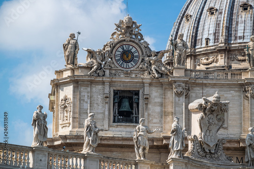 view on Dome of St. Peter's Basilica with statues of apostles chapel with bell and old clock in Vatican City, Italy