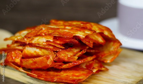 Balado Spicy Chips (cassava crackers) on wood background and a cup of drink.