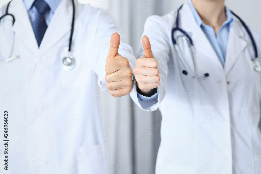 Team of unknown medicine doctors showing OK sign with thumb up close up. Success and high level service in health care, best treatment and customer loyalty and physical concept Team of unknown medicine doctors showing OK sign with thumb up close up. Success and high level service in health care, best treatment and customer loyalty and physical concept