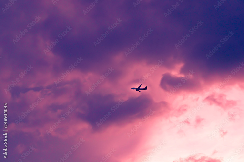An airplane flying through the clouds at sunset 