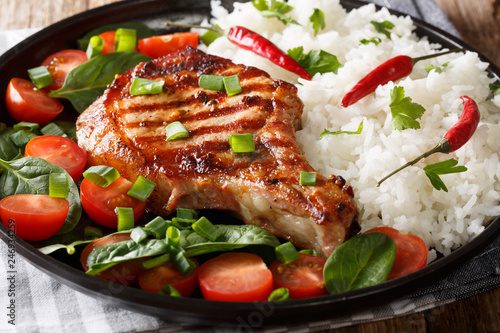 grilled pork chop cutlet with rice and fresh vegetable salad close-up on a plate. horizontal