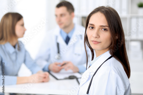 Young beautiful female doctor smiling  on the background with patient  in hospital