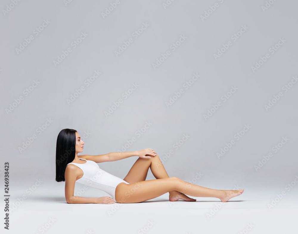 Beautiful fashion model in white swimsuit and hosiery. Young and beautiful woman posing in studio. Beautiful fashion model in white swimsuit and hosiery. Young and beautiful woman posing in studio.
