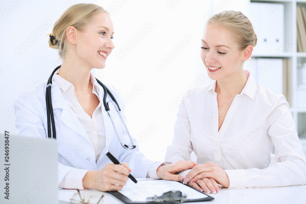 Doctor and patient talking in hospital office while sitting at the desk. Health care and client service in medicine Doctor and patient talking in hospital office while sitting at the desk. Health care and client service in medicine