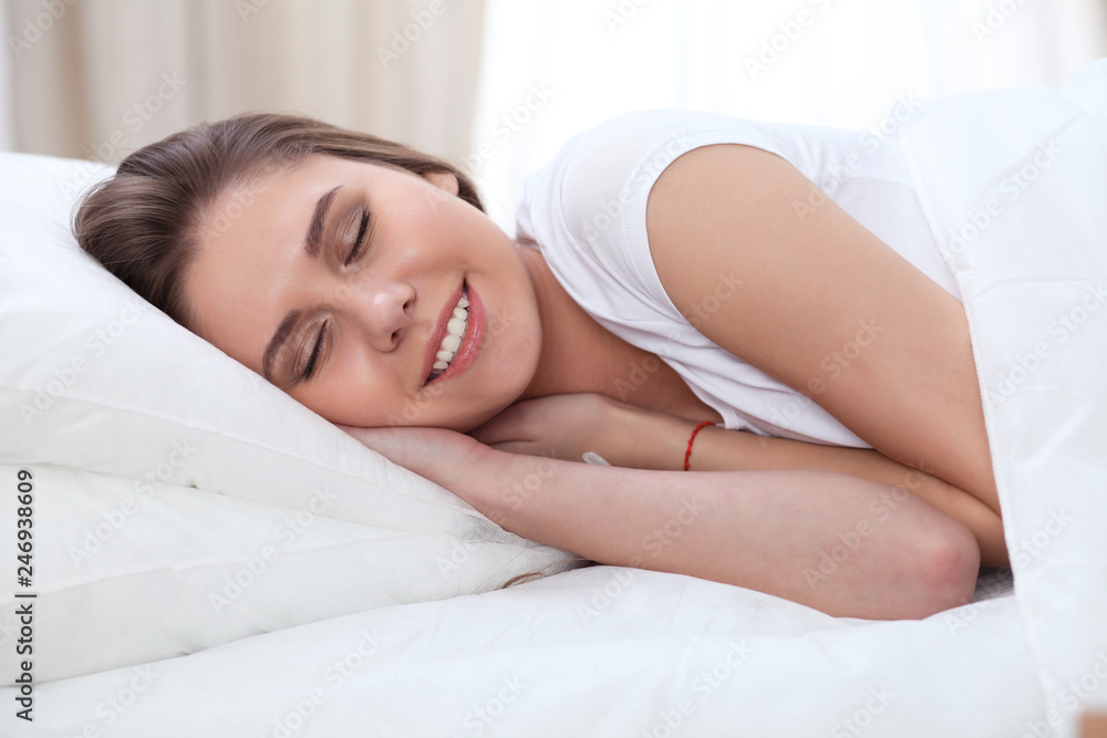 Beautiful young and happy woman sleeping while lying in bed comfortably and blissfully smiling Beautiful young and happy woman sleeping while lying in bed comfortably and blissfully smiling
