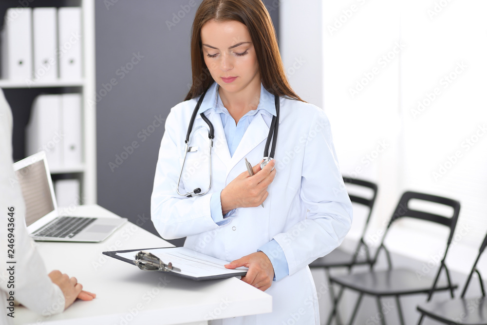 Doctor woman at work. Portrait of female physician standing near reception desk at clinic or emergency hospital. Medicine and healthcare concept Doctor woman at work. Portrait of female physician standing near reception desk at clinic or emergency hospital. Medicine and healthcare concept