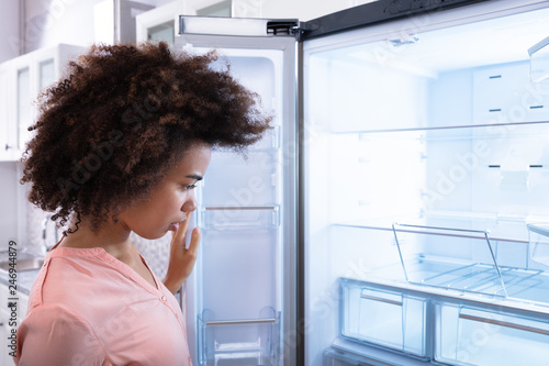 African Woman Looking At Empty Refrigerator