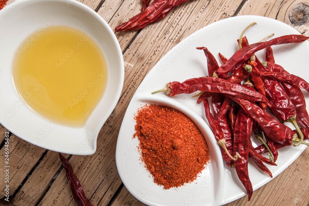 Olives oil and red chili pepper in bowl on wood rustic background, top view Olives oil and red chili pepper in bowl on wood rustic background, top view