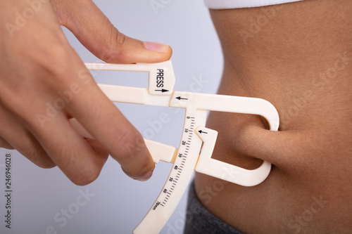 Woman Measuring Her Body Fat With Caliper