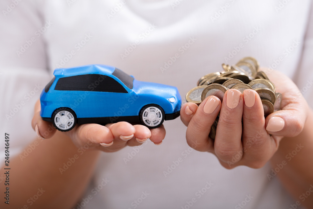 Fototapeta premium Woman Holding Blue Car And Coins