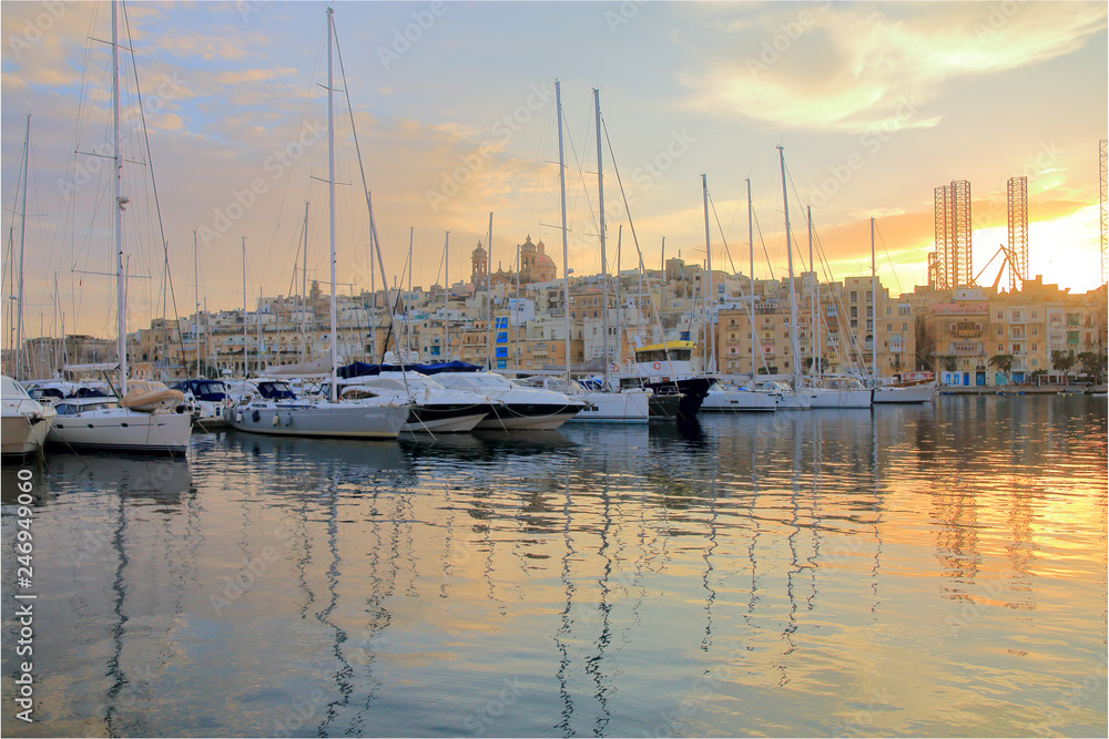 Yachts moored in the harbor of Malta in the rays of the setting sun.