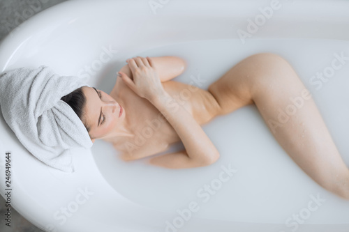 Sensual brunette business lady taking homemade skin care spa procedure in bathroom, enjoying with milky aromatic bath and rare moments of peace and quiet.