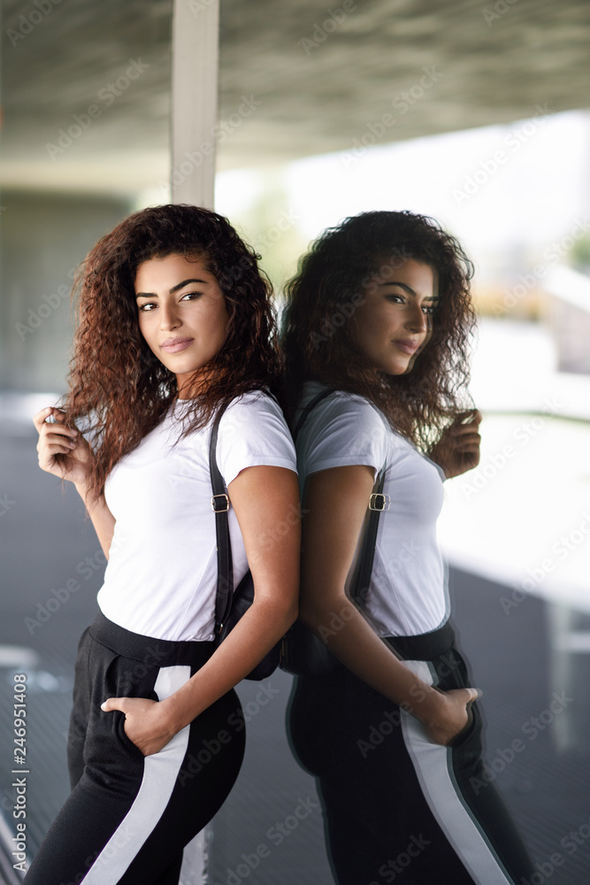 Obraz premium Young African woman with black curly hairstyle standing near business building