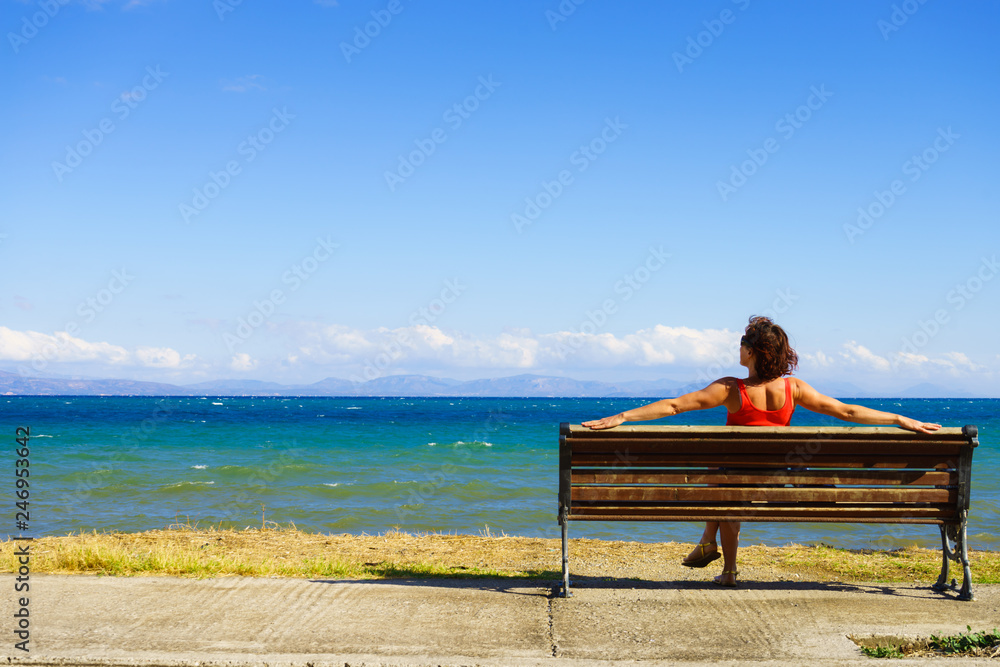 Tourist woman on bench enjoying sea view