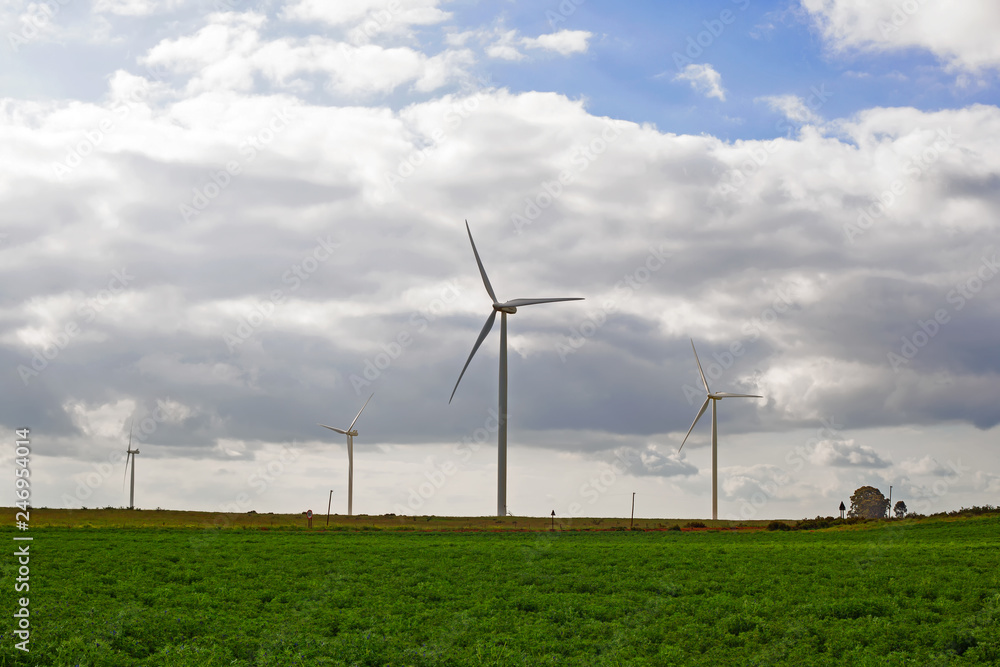 Wind turbines with green field and cloudy sky Wind turbines with green field and cloudy sky