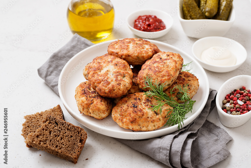 Juicy delicious meat cutlets in a white plate on a light gray table. 