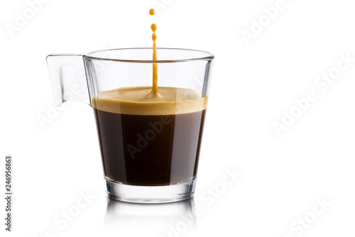 Czarna kawa w szklanej filiżance z doskakiwanie kroplą na białym tle