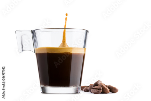 Black coffee in glass cup with coffee beans and jumping drop on white background