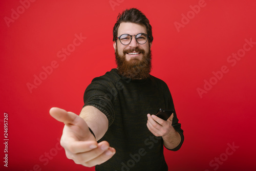 Portrait of cheerful bearded man .stretches his hand, inviting handsome