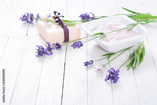 pink moisturizer cream  soap bar and purple lavender flowers on white rusty wooden table background