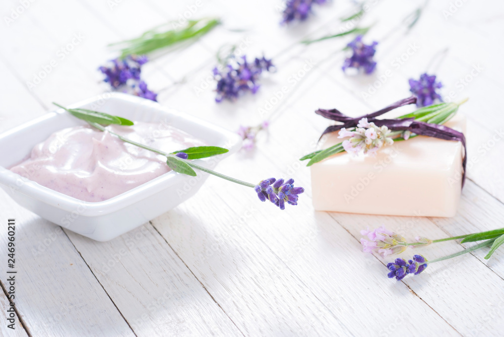 pink moisturizer cream, soap bar and purple lavender flowers on white rusty wooden table background pink moisturizer cream, soap bar and purple lavender flowers on white rusty wooden table background