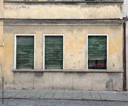 three windows with shutters broken of an old house with a case o