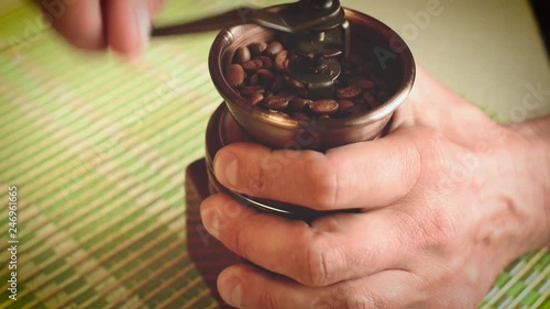 Male hands using a hand mill to grind coffee beans. 