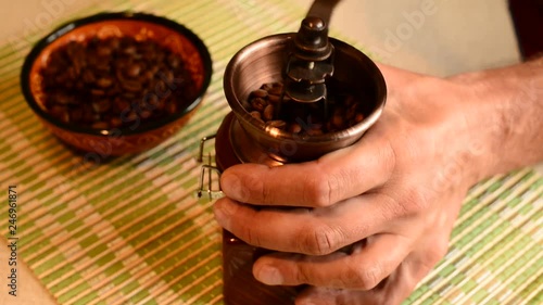 Male hands using a hand mill to grind coffee beans. 