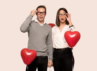 Couple in valentine day with glasses and surprised over isolated background