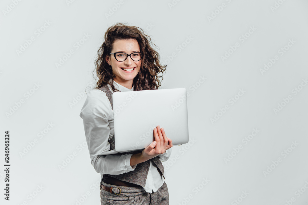 BBeautiful young girl smiles. Works on a laptop in glasses and a white shirt BBeautiful young girl smiles. Works on a laptop in glasses and a white shirt