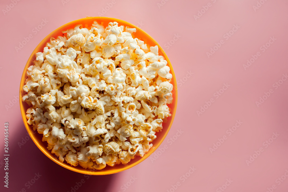 An orange bowl with popcorn isolated on pink background An orange bowl with popcorn isolated on pink background