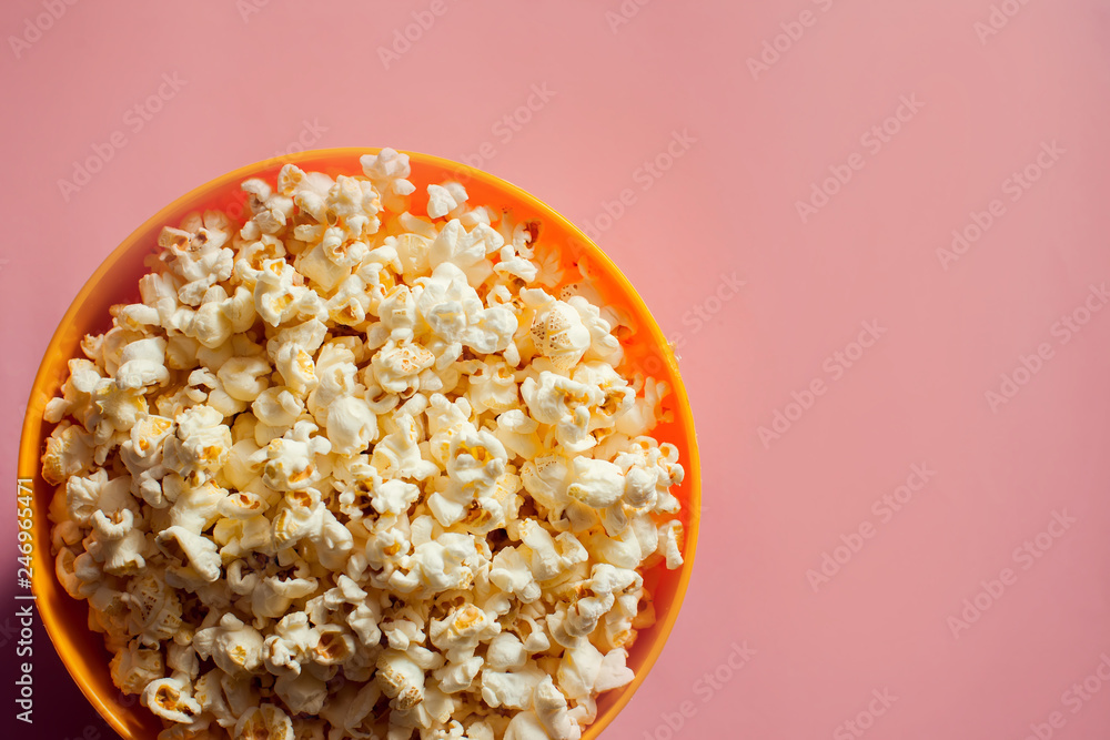 An orange bowl with popcorn isolated on pink background An orange bowl with popcorn isolated on pink background