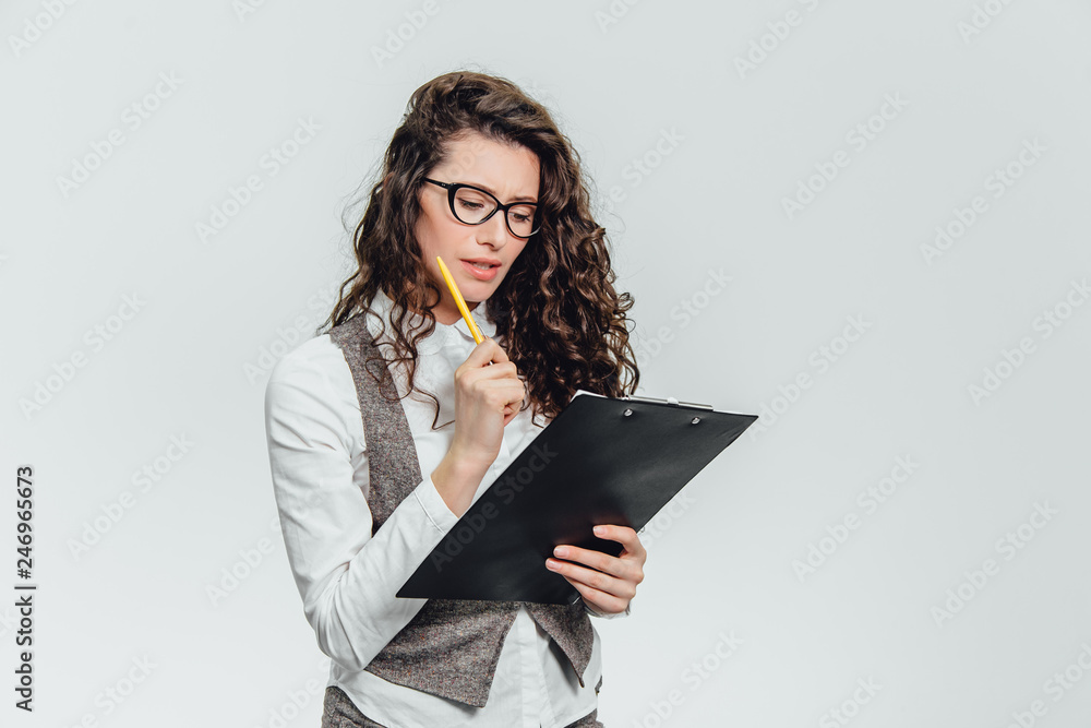 Happy beautiful young business woman standing. Holding clipboard over white background . Happy beautiful young business woman standing. Holding clipboard over white background .