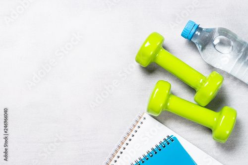 Dumbbells, notepad, water and apple top view. 