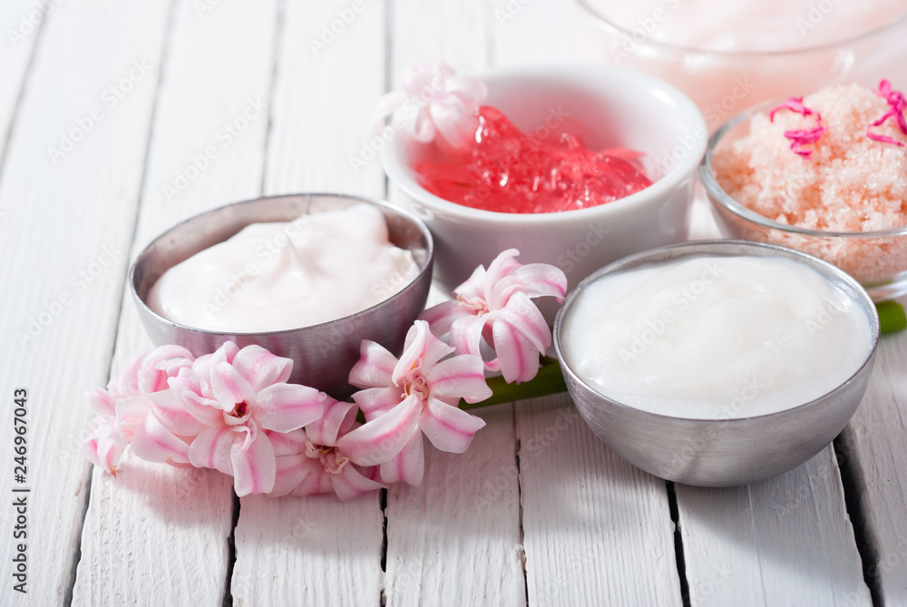 beauty and cosmetic creams with pink flowers on white wood beauty and cosmetic creams with pink flowers on white wood