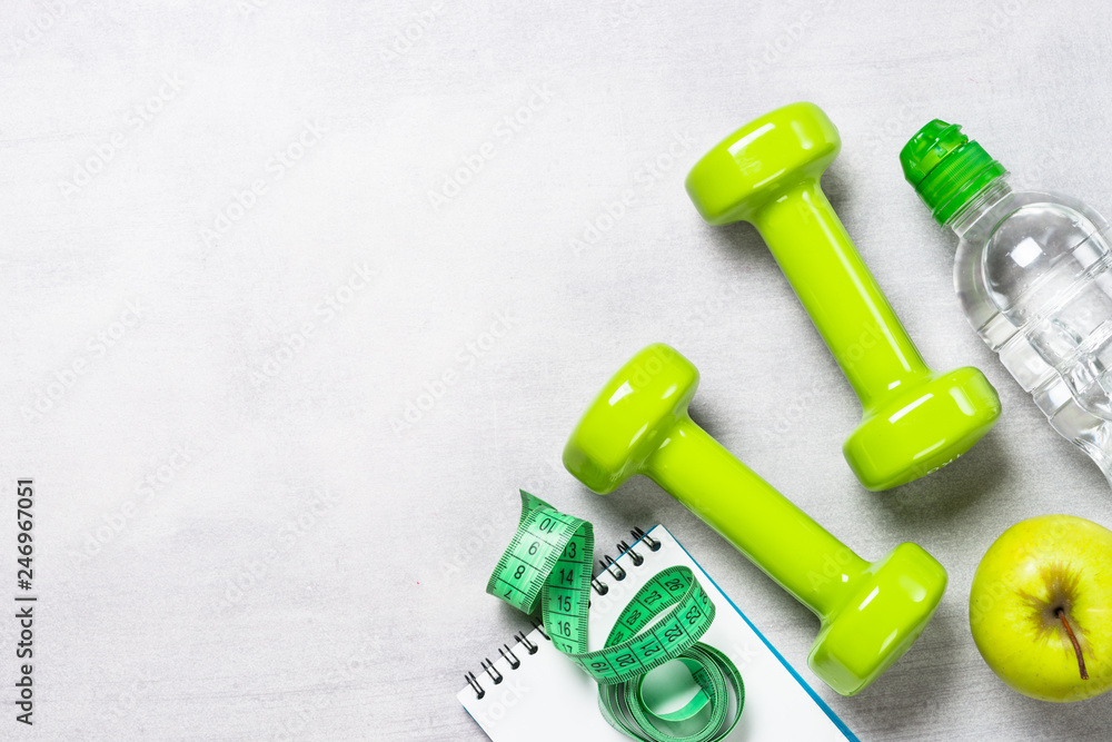 Dumbbells, measuring tape, water and apple top view. Dumbbells, measuring tape, water and apple top view.