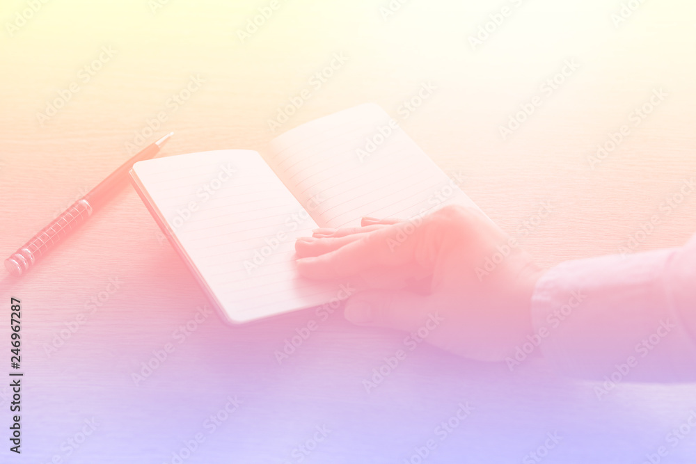 Hand holding an opened notebook, toned photo in soft pink tones Hand holding an opened notebook, toned photo in soft pink tones
