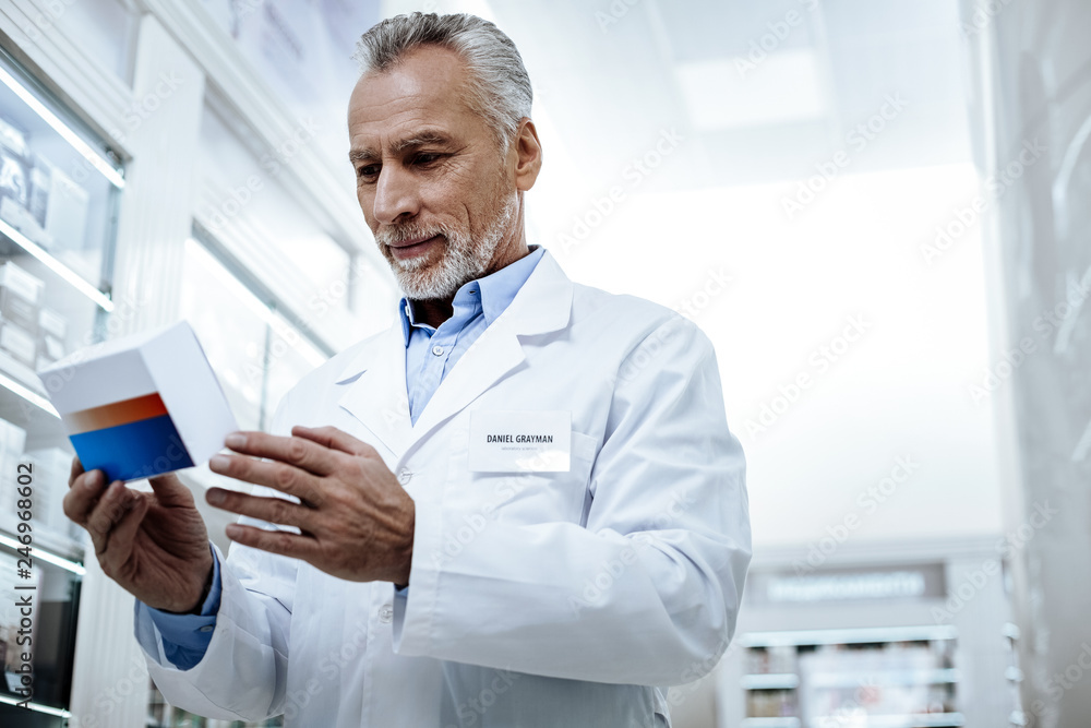 Bearded handsome man in a white coat presenting a new medicine Bearded handsome man in a white coat presenting a new medicine