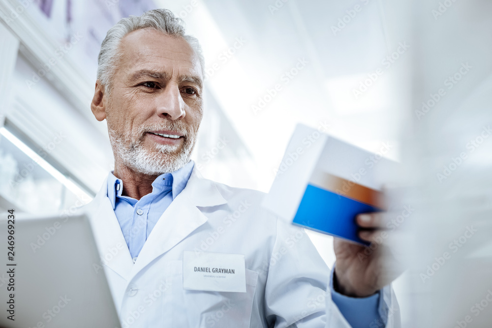 Handsome bearded smiling man in a white coat investigating the medicine Handsome bearded smiling man in a white coat investigating the medicine