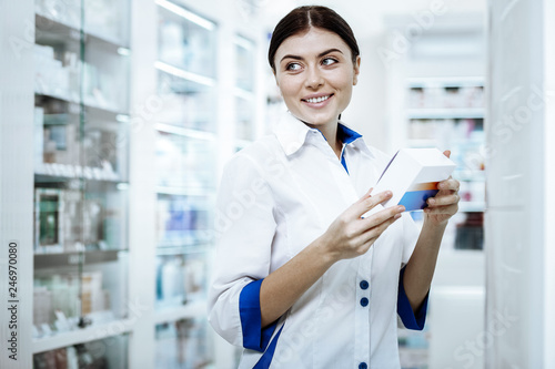 Cute long-haired woman in a white coat smiling to a client photo