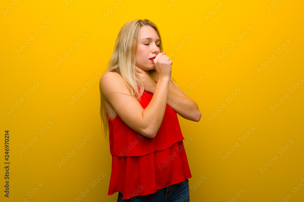 Young girl with red dress over yellow wall is suffering with cough and feeling bad Young girl with red dress over yellow wall is suffering with cough and feeling bad