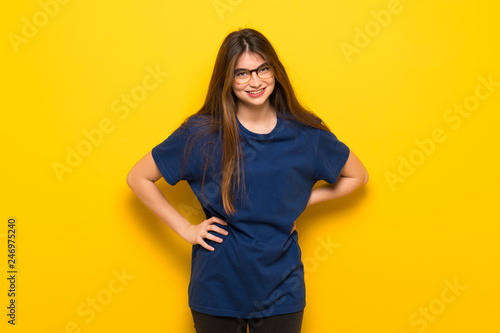 Young woman with glasses over yellow wall happy and smiling © luismolinero