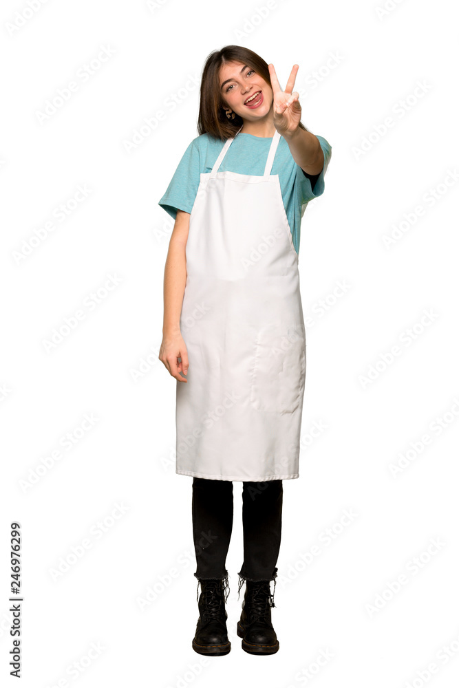 Full-length shot of Girl with apron smiling and showing victory sign on isolated white background Full-length shot of Girl with apron smiling and showing victory sign on isolated white background