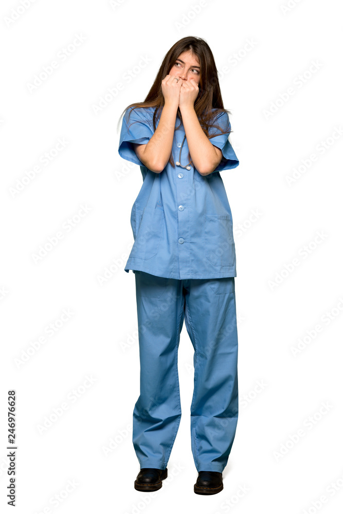 Full-length shot of Young nurse is a little bit nervous and scared putting hands to mouth on isolated white background Full-length shot of Young nurse is a little bit nervous and scared putting hands to mouth on isolated white background