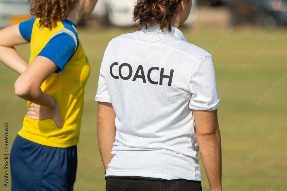 Back of sport coach wearing COACH shirt at an outdoor sport field Back of sport coach wearing COACH shirt at an outdoor sport field